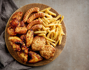 Image showing various fried meat and potatoes on wooden board