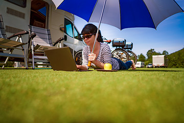 Image showing Woman on the grass, looking at the laptop under umbrella near th