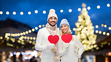 Image showing couple with red hearts over christmas tree lights