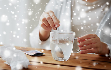 Image showing ill woman stirring medication in cup with spoon