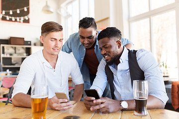 Image showing male friends with smartphone drinking beer at bar