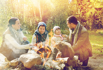 Image showing happy family roasting marshmallow over campfire