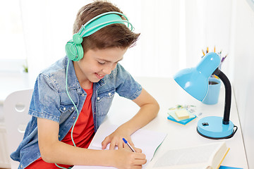 Image showing student boy in headphones writing to notebook