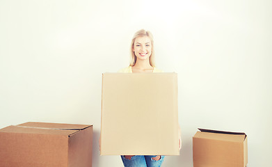 Image showing smiling young woman with cardboard box at home