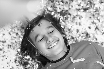 Image showing kid blowing confetti while lying on the floor