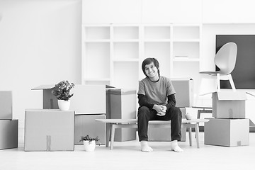 Image showing boy sitting on the table with cardboard boxes around him