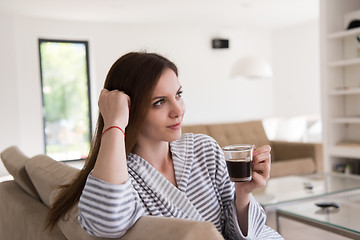 Image showing young woman in a bathrobe enjoying morning coffee