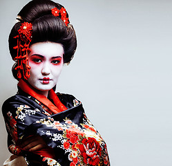 Image showing young pretty geisha in kimono with sakura and red decoration des