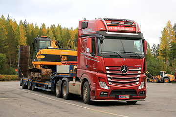 Image showing Red Mercedes-Benz Actros Hauls JCB Excavator on Trailer