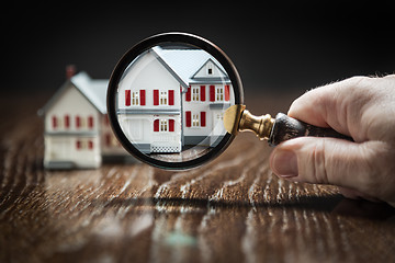 Image showing Hand Holding Magnifying Glass Up To Model Home on Reflective Woo