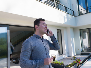 Image showing man using mobile phone in front of his luxury home villa