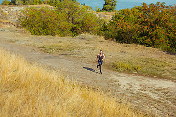 Image showing Running sport. Man runner sprinting outdoor in scenic nature. Fit muscular male athlete training trail running for marathon run.