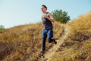 Image showing Running sport. Man runner sprinting outdoor in scenic nature. Fit muscular male athlete training trail running for marathon run.