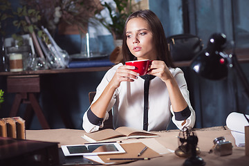 Image showing Young beautiful woman working with cup of coffee