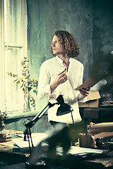 Image showing Writer at work. Handsome young writer standing near the table and making up something in his mind