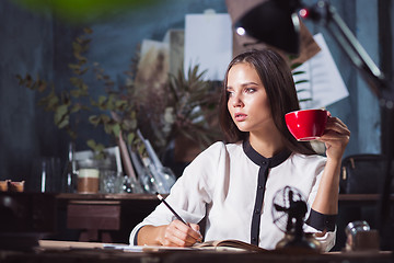 Image showing Young beautiful woman working with cup of coffee