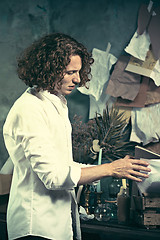 Image showing Writer at work. Handsome young writer standing near the table and making up something in his mind