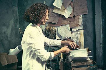 Image showing Writer at work. Handsome young writer standing near the table and making up something in his mind