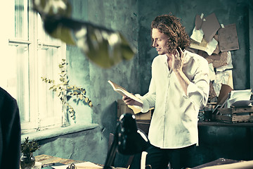 Image showing Writer at work. Handsome young writer standing near the table and making up something in his mind