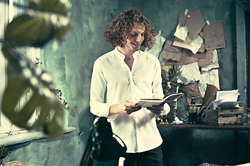 Image showing Writer at work. Handsome young writer standing near the table and making up something in his mind