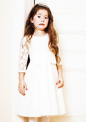 Image showing little cute girl at home, opening door well-dressed in white dre