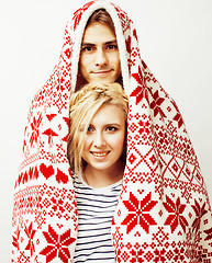 Image showing young pretty teenage couple at Christmas time warming in red decorated blanket, hipster guy with his girlfriend happy smiling and hugging isolated on white background, lifestyle people concept 