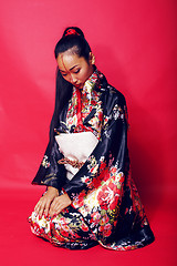 Image showing young pretty geisha on red background posing in kimono, oriental people concept