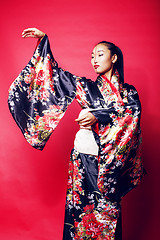 Image showing young pretty geisha on red background posing in kimono, oriental people concept