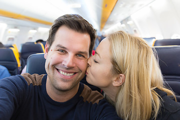 Image showing Young handsome couple taking a selfie on commercial airplane.
