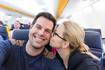 Image showing Young handsome couple taking a selfie on commercial airplane.