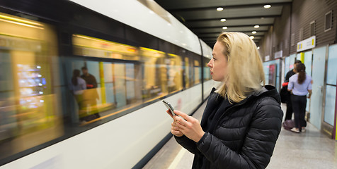 Image showing Woman with a cell phone waiting for metro.