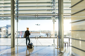 Image showing Young woman waiting at airport, looking through the gate window.