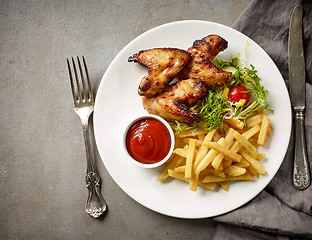 Image showing Plate of fried potatoes and chicken wings