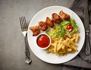 Image showing Plate of fried potatoes and pork kebab