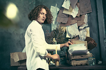 Image showing Writer at work. Handsome young writer standing near the table and making up something in his mind