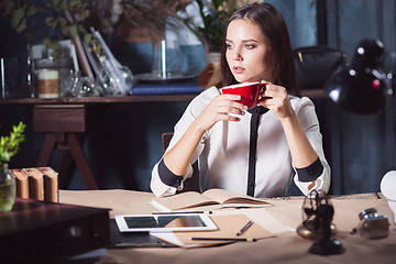 Image showing Young beautiful woman working with cup of coffee