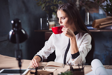 Image showing Young beautiful woman working with cup of coffee