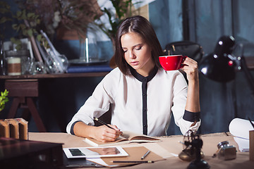 Image showing Young beautiful woman working with cup of coffee