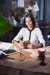 Image showing Young beautiful woman working with cup of coffee