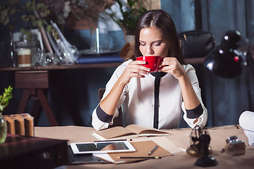 Image showing Young beautiful woman working with cup of coffee