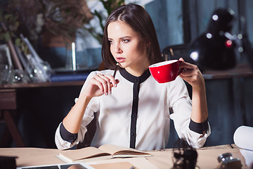 Image showing Young beautiful woman working with cup of coffee