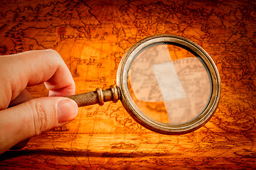 Image showing Vintage magnifying glass lies on an ancient world map