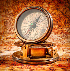 Image showing Vintage compass lies on an ancient world map.