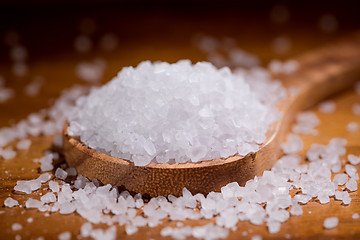 Image showing Sea salt crystals closeup in wooden spoon on a kitchen table.