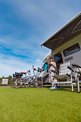 Image showing Woman is standing with a mug of coffee near the camper RV.