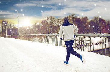 Image showing man running along snow covered winter bridge road