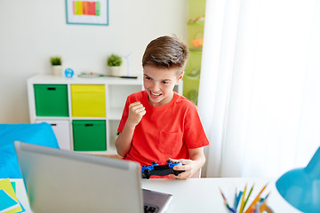 Image showing boy with gamepad playing video game on laptop