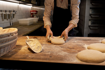 Image showing baker portioning dough with bench cutter at bakery