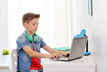 Image showing boy with headphones typing on laptop at home