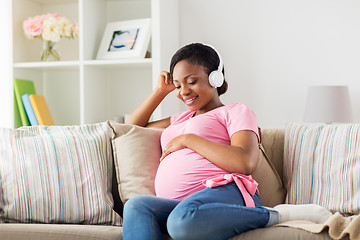 Image showing pregnant woman in headphones at home